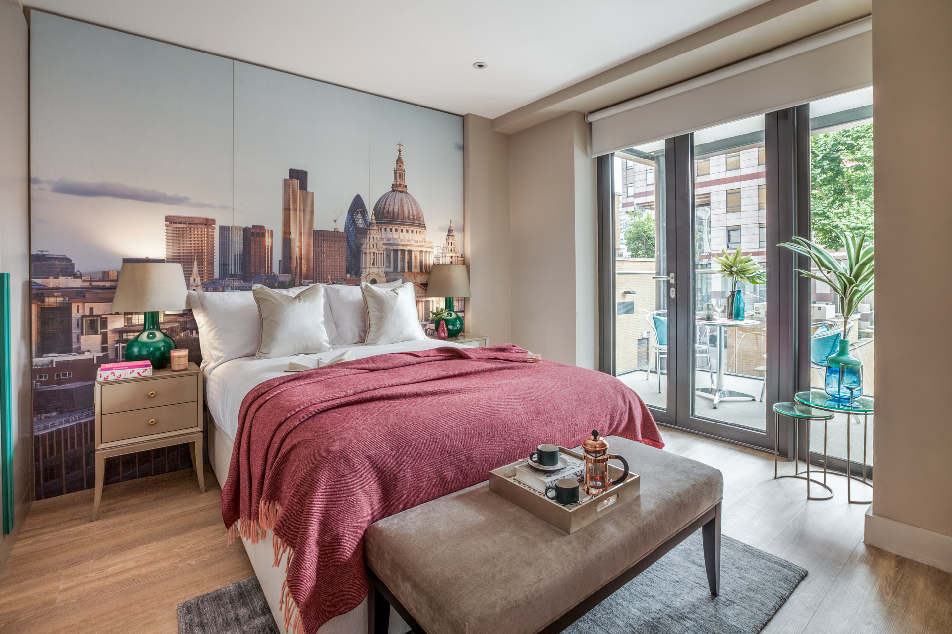 Bedroom with private balcony, with modern interior scheme of reds, greens and beige