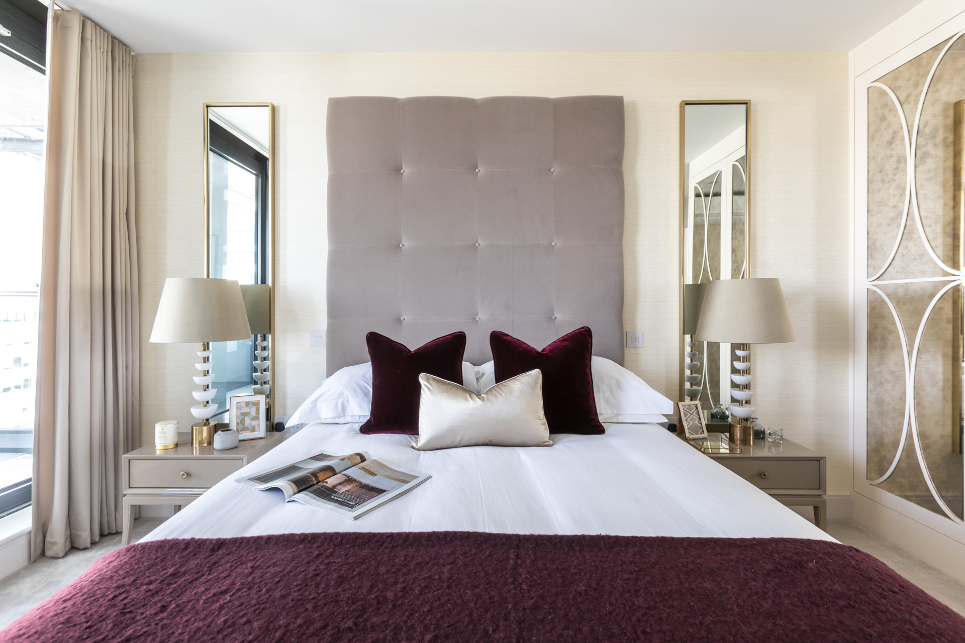 professionally styled master bedroom with full height headboard in purple gold and grey.