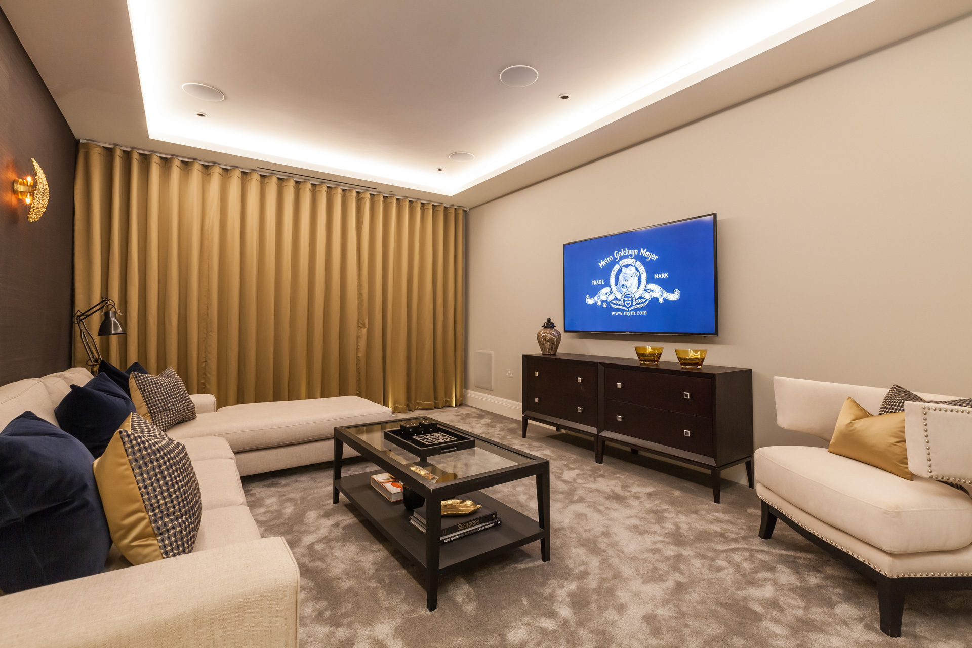 tv room with curtain, blue and yellow scatter cushions on a cream L-shaped sofa and Dark brown wood furniture